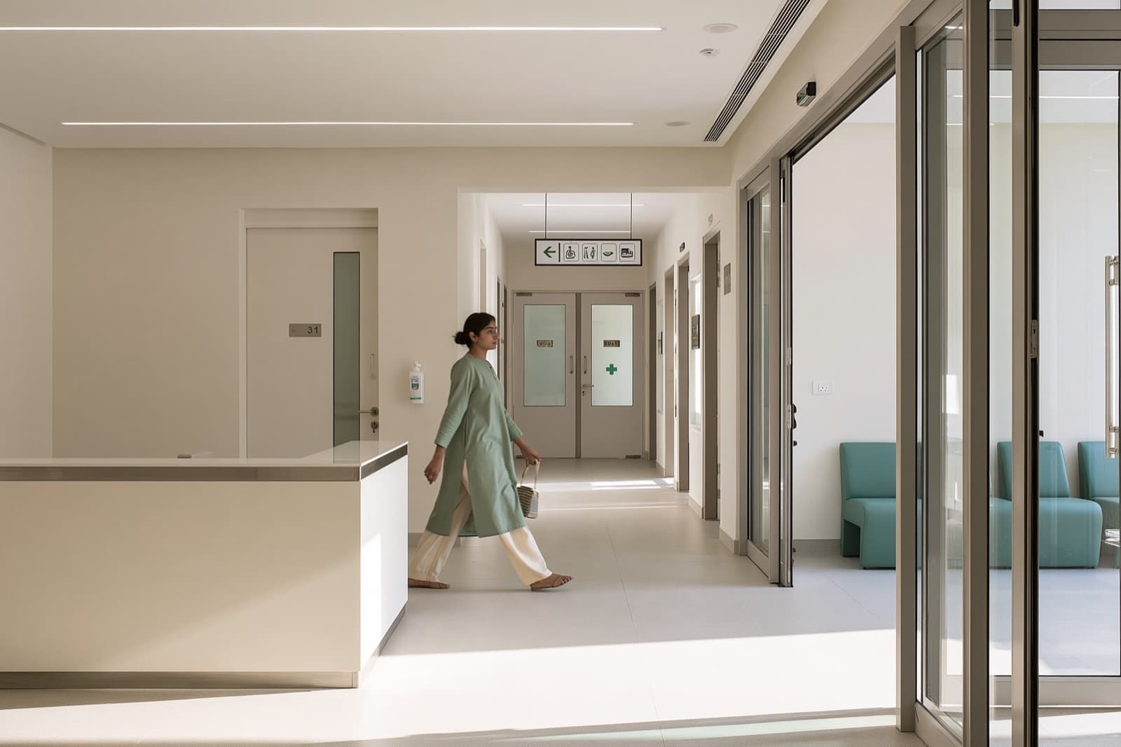A patient walking past the reception desk of a bright, modern clinic